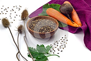 Milk thistle seeds in wooden bowl, thirstle dry herbs, carrot and beetroot