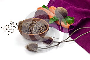 Milk thistle seeds in wooden bowl, thirstle dry herbs, carrot and beetroot