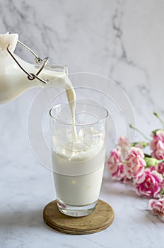 The milk was poured into a glass placed on a marble floor and had carnations. Cold brew iced milk in glass bottles