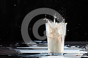 Milk or white liquid splash and oat flakes, muesli in the glass on a black background