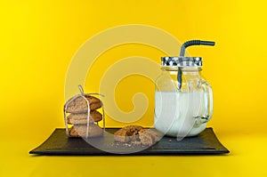 Milkshake in glass jar and oatmeal cookies on yellow background, concept of natural products, healthy food, closeup, copy space