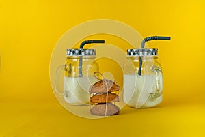 Milkshake in glass jar and oatmeal cookies on yellow background, concept of natural products, healthy food, closeup, copy space