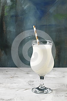 Milkshake or milk cocktail with ice cream and natural vanilla, blue background, copy space, selective focus