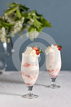 Milkshake with strawberry and flowers on background