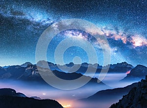 Milky Way above mountains in fog at night in summer