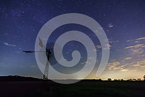 The milky way core rises above a windmill in central Germany