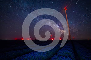 The milky way galaxy stars seen in a lavander field with eolian turbines