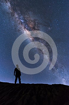 Milky Way landscape. Silhouette of Happy man standing on top of mountain with night sky and bright star on background