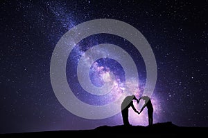 Milky Way. Man and woman holding hands in heart shape