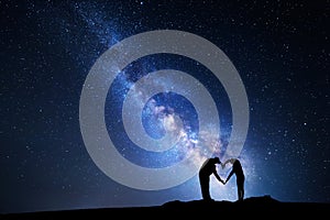 Milky Way. Man and woman holding hands in heart shape