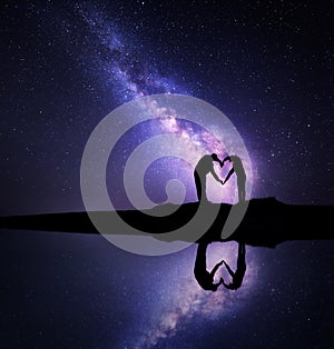 Milky Way. Man and woman holding hands in heart shape