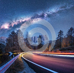 Milky Way over mountain road. Blurred car headlights