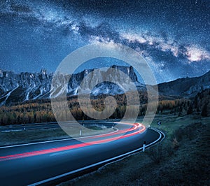 Milky Way over mountain road. Blurred car headlights