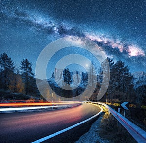 Milky Way over mountain road. Blurred car headlights