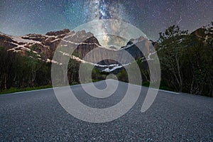 Milky way over mountains at the end of a long road.