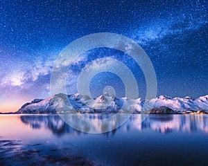 Milky Way over snow covered mountains and sea at night in winter
