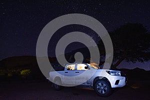 Milky way over a tent located on the roof of a pickup car in the Namib desert in Namibia. Night photo with many stars.