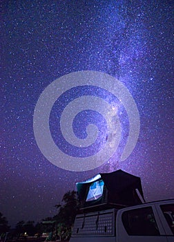 Milky way over a tent on the roof of a pickup car in the Namib desert of Namibia