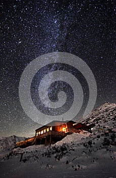 Milky way over winter mountain landscape with cottage, Slovakia