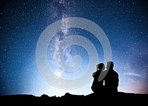 Milky Way with silhouette of people. Landscape with night starry sky. Standing man and woman on the mountain with star