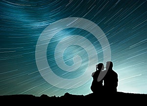 Milky Way with silhouette of people. Landscape with night starry sky. Standing man and woman on the mountain with star