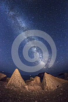 Milky way sky on beach with big rocks