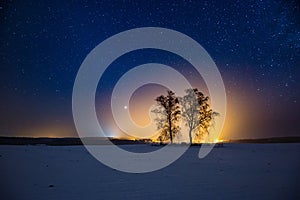 Milky way and starry sky over winter landscape and distant village