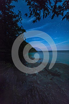 Milky way and starry sky with wispy clouds along the lakeshore o