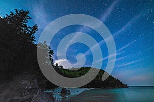 Milky way and starry sky with wispy clouds along the lakeshore o