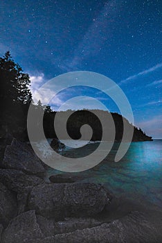 Milky way and starry sky with wispy clouds along the lakeshore o