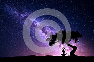 Milky Way with tree and woman practicing yoga