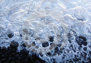 A milky white tide breaking on the rocky shore