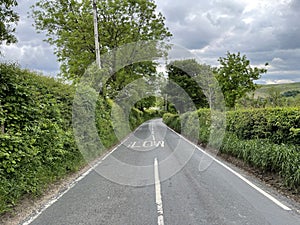 Mill Lane, with green hedgerow, and distant hills in, Hawksworth, Leeds, UK