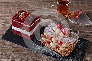 Mille feuille dessert sweet slice red velvet cake with white frosting is garnished with strawberries