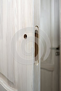 Milled and drilled hole in a wooden door, prepared for the installation of a lock