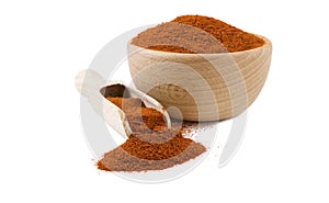 Milled or ground paprika or red peppe in wooden bowl and scoop isolated on white background. Spices and food ingredients