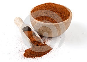Milled or ground paprika or red pepper in wooden bowl and scoop isolated on white background. Spices and food ingredients