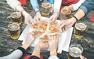 Millenial friends group drinking beer and sharing pizza slices at bar restaurant - Friendship concept with young people having fun