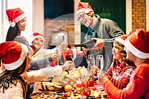 Millenial friends on santa hats celebrating Christmas with champagne and sweets food at log cabin - Winter holidays concept