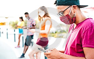 Millenial friends wearing disposable face mask using tracking app with mobile phones