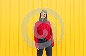 Millenial girl im fashionable clothes having a good time, making funny faces near bright yellow urban wall.