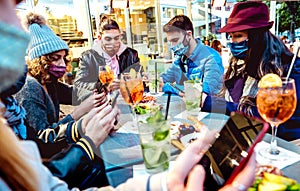 Millenial people using mobile smart phones at cocktail bar - New normal lifestyle concept with friends on contact tracing app