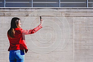 Millenial woman taking a selfie with happy gesture to pretend to be successful in life