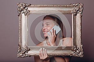 Millenial young woman blonde hair holds gilded picture frame in hands face portrait