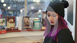 Millenials lifestyle. Portrait of stunning asian woman with bright red lips and purple hair reading a book in a