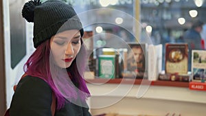 Millenials lifestyle. Portrait of stunning asian woman with bright red lips and purple hair reading a book in a