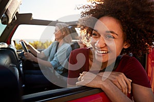 Millennial African American woman on a road trip with friends, leaning out of car window, close up