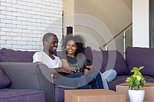 Millennial african couple sitting resting on couch on moving day