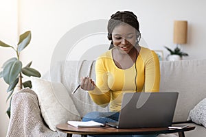 Millennial African Lady In Headset Watching Online Webinar On Laptop At Home