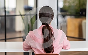 Millennial arab businesswoman hr manager at empty desk in modern coworking office, back